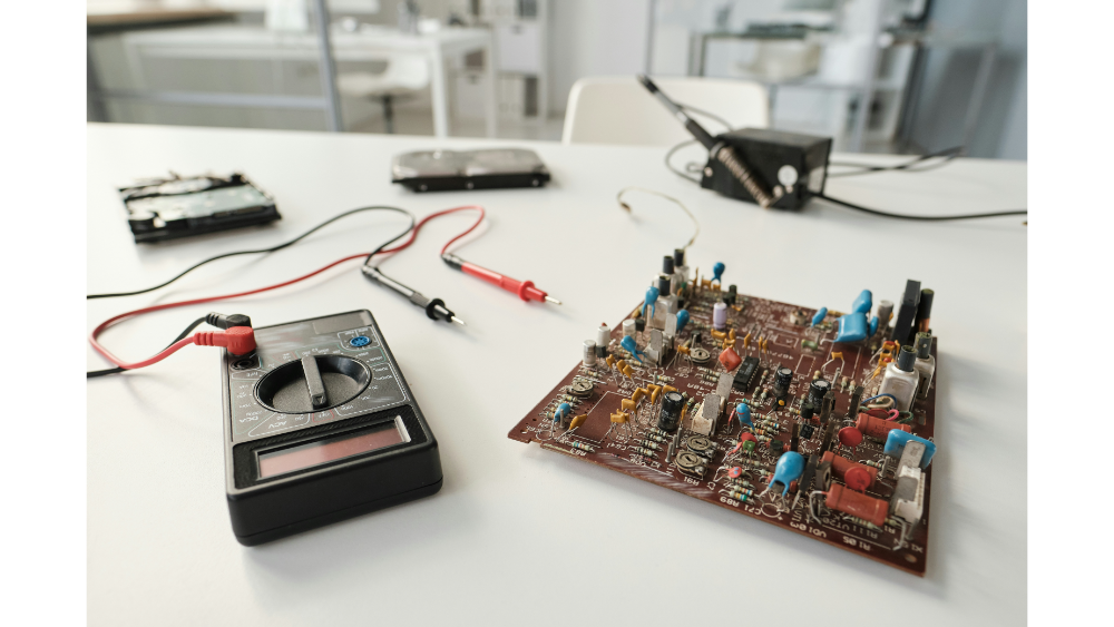 Electronics workbench with a circuit board, multimeter, and probes, set up for testing in a bright, modern lab environment.