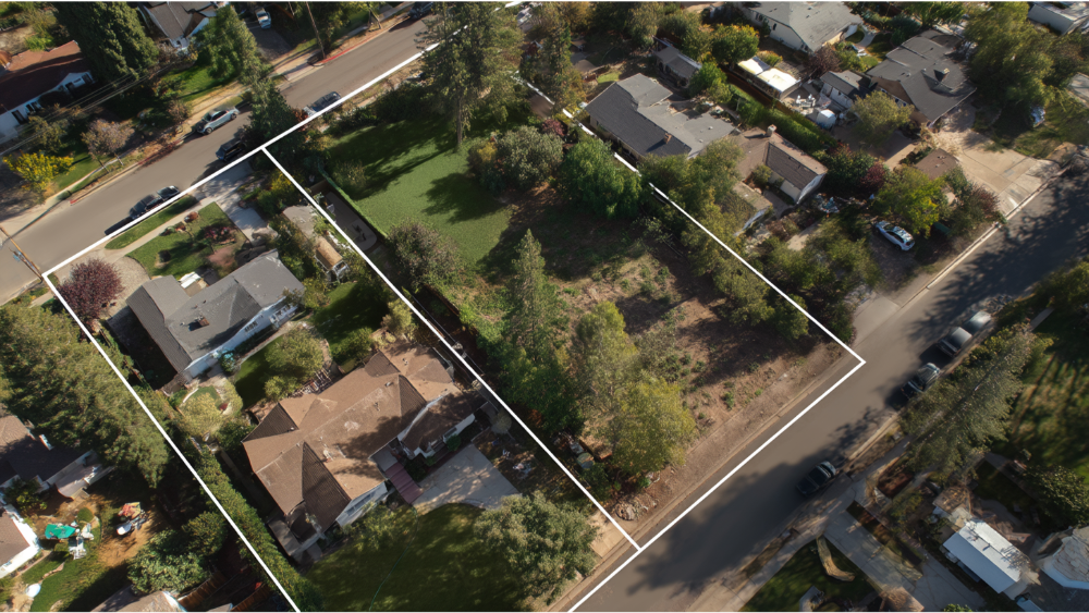 Aerial view of two adjacent residential lots outlined in white, showing land division and surrounding neighborhood streets.