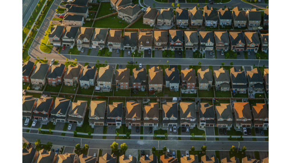 Aerial view of a dense residential neighborhood with rows of attached and semi-detached houses at sunset.
