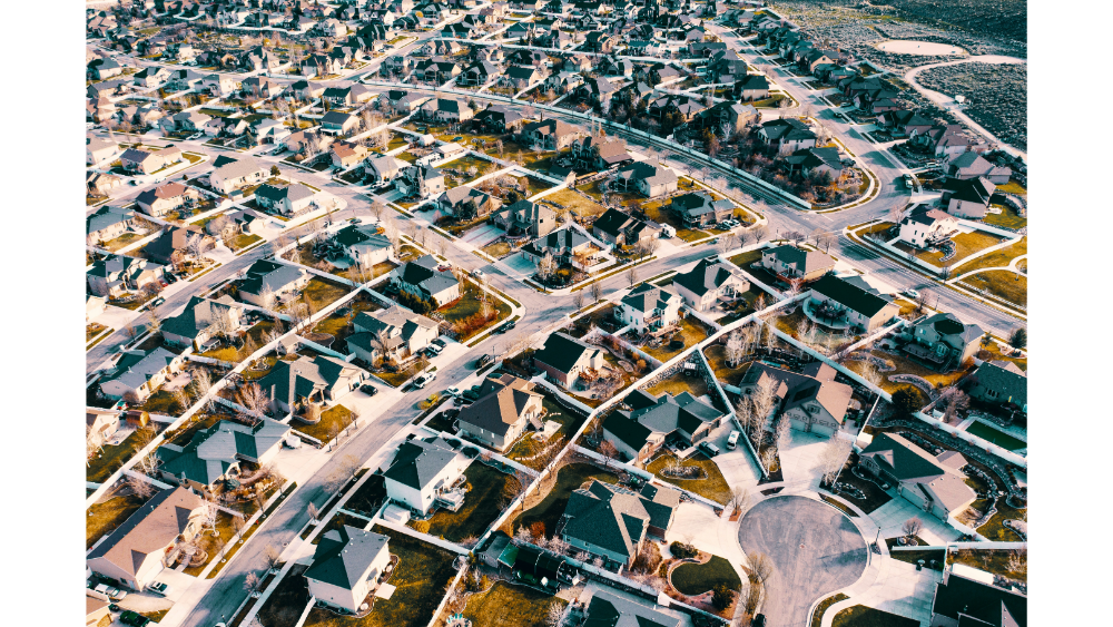 Aerial view of a large suburban neighborhood with curved streets, single-family homes, and fenced yards.