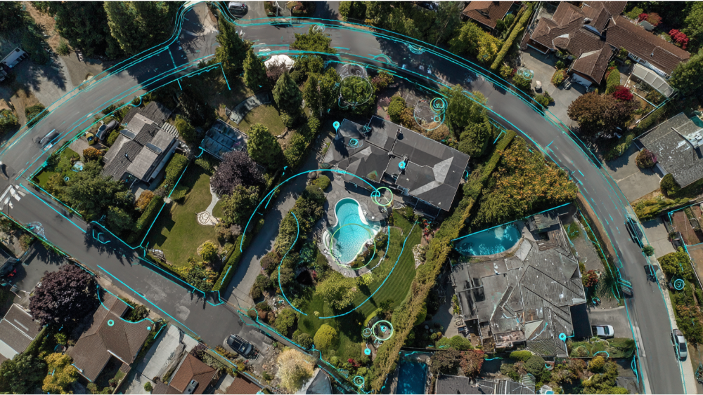 Drone view of a residential neighborhood with property boundaries and digital overlays highlighting lot lines and structures.